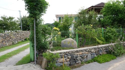 a garden with a stone fence and flowers at Buan sukranjeong pension in Buan
