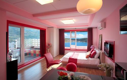 a pink bedroom with a bed and a large window at Namhae Elnido Pension in Namhae