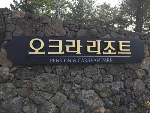 un panneau pour un parc sur un mur de pierre dans l'établissement Seogwipo Okra Resort, à Seogwipo