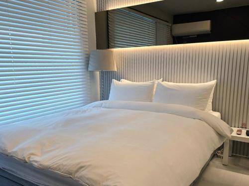 a large white bed in a bedroom with a window at Penates Poolvilla A in Chungju