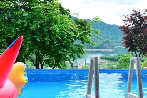 a swimming pool with a view of a lake at Penates Poolvilla A in Chungju