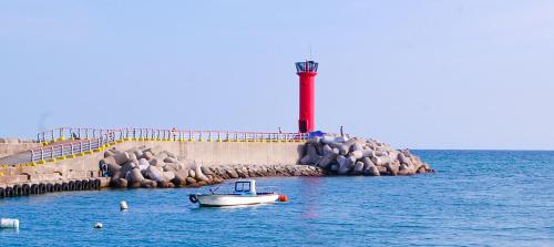 a boat in the water in front of a lighthouse at Ulsan Lighthouse Pension in Ulsan