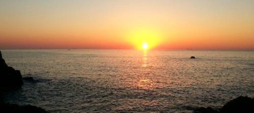 a sunset over the ocean with the sun setting at Ulsan Lighthouse Pension in Ulsan