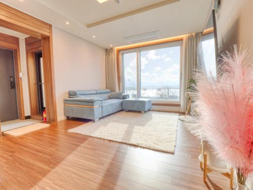 a living room with a blue couch and a large window at Chuncheon Kerensia Pension in Chuncheon