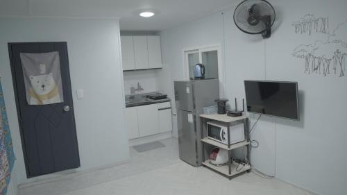 a kitchen with a refrigerator and a tv in it at Gapyeong Gumuchon Amusement Park Pension in Gapyeong