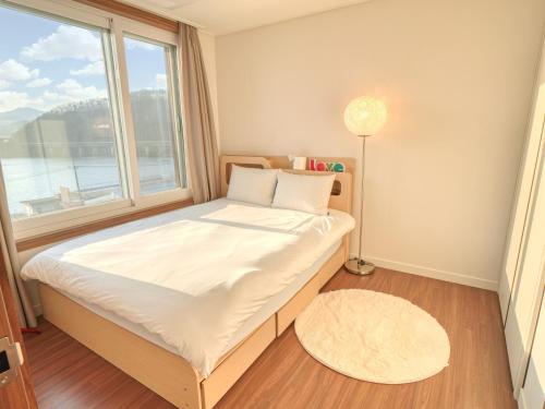 a small bedroom with a bed with a window at Chuncheon Kerensia Pension in Chuncheon