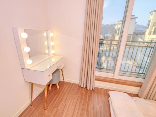 a dressing table with a mirror in a room with a window at Chuncheon Kerensia Pension in Chuncheon