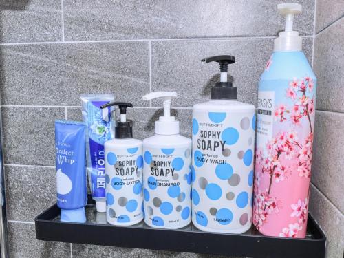 a shelf with four bottles of soap and toothbrushes at Chuncheon Kerensia Pension in Chuncheon