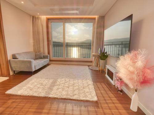 a living room with a chair and a large window at Chuncheon Kerensia Pension in Chuncheon