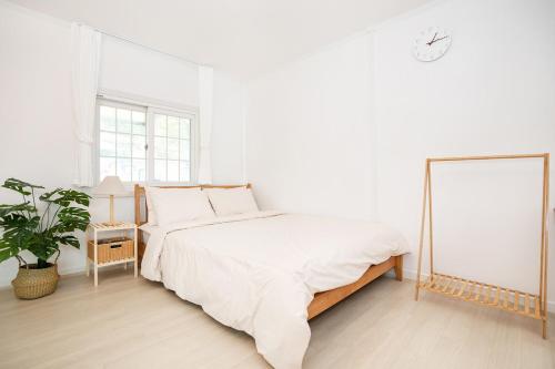 a white bedroom with a large bed and a plant at Sweet Pension Yangyang in Yangyang