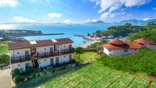 a house on a hill next to a body of water at Namhae New Island Pension in Namhae