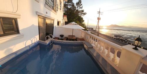 a swimming pool next to a building with a view of the ocean at Yeosu Sound of Music Pension in Yeosu