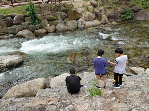 three people standing on rocks looking at a river at Danyang mulgoeul pension in Danyang