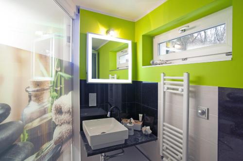 a bathroom with green walls and a sink and a mirror at Designpension Idyll Nr2 Hotel Garni in Wernigerode