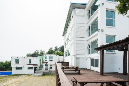 a large white building with a deck and benches at Incheon donggeumdo hanguk villa in Incheon