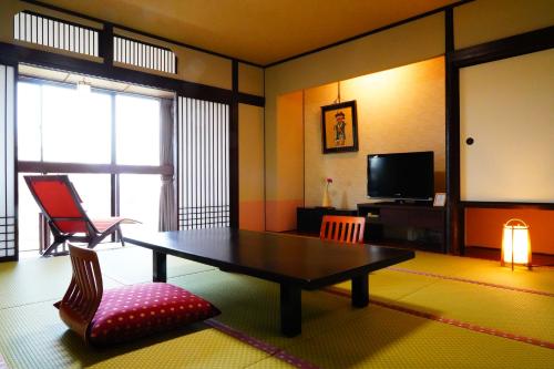 a living room with a table and a flat screen tv at Dantokan Kikunoya in Otsu