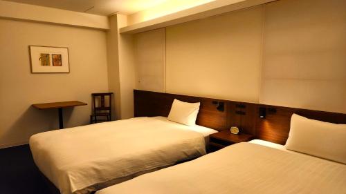 a hotel room with two beds and a table at Shin-Osaka Station Hotel in Osaka