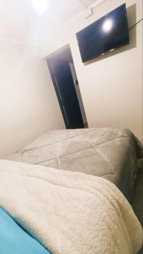 a bed in a room with a light on the wall at Alojamiento familiar Ñuñoa con estacionamiento a pasos del Estadio Nacional e ISP in Santiago