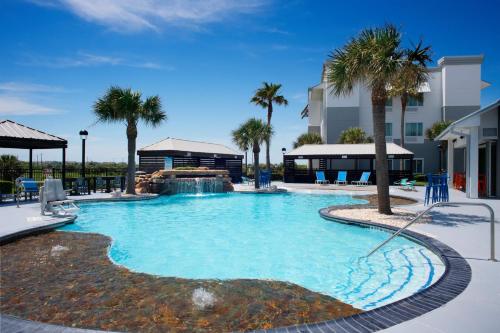 a large swimming pool with a waterfall and palm trees at TownePlace Suites by Marriott Galveston Island in Galveston