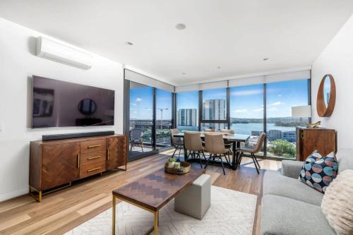 a living room with a large tv and a table with chairs at Sensational City Apartment with Lake Views in Canberra