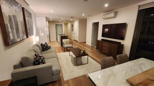 a living room with a couch and a flat screen tv at Sensational City Apartment with Lake Views in Canberra