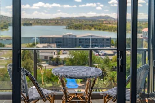 a table and chairs on a balcony with a view at Sensational City Apartment with Lake Views in Canberra