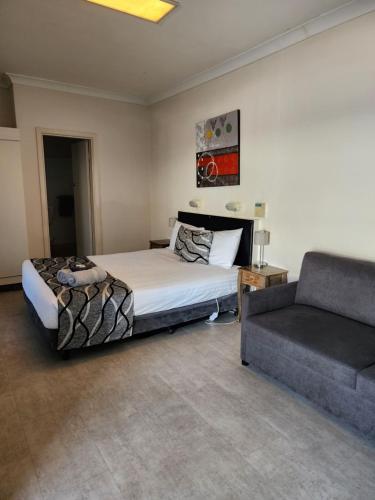 a bedroom with a bed and a couch at Inverell Motel in Inverell