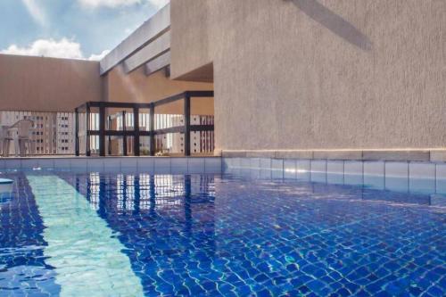 a large swimming pool next to a building at Apartamento Confortável em Guaratinguetá in Guaratinguetá