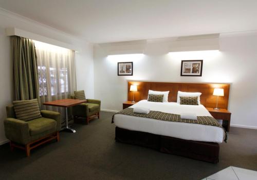 a hotel room with a bed and two chairs at Chinchilla Downtown Motor Inn in Chinchilla