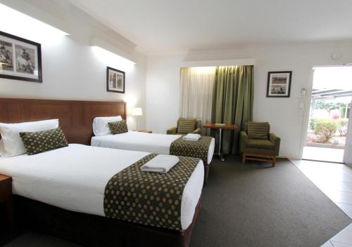 a hotel room with two beds and two chairs at Chinchilla Downtown Motor Inn in Chinchilla
