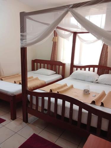 a bedroom with two beds and a canopy bed at One World Apartments in Mombasa