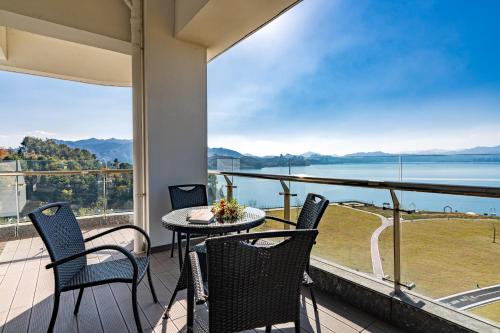 a balcony with a table and chairs and a view of the water at Huangshan Taiping Lake Muxin Hotel in Fenghuangshan