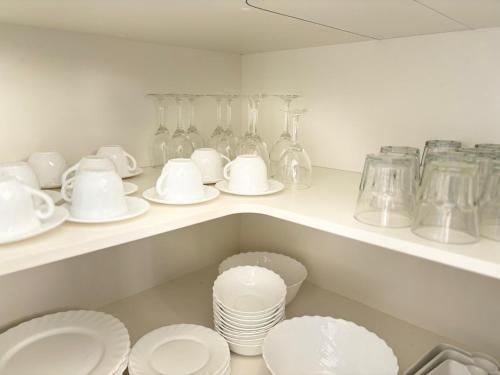 a kitchen with white plates and glass vases on a shelf at Kowhai Motel Rotorua in Rotorua
