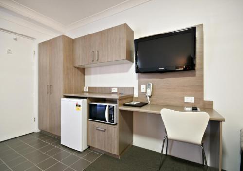 a kitchen with a desk with a microwave and a refrigerator at The Aberdeen Motel in Dubbo