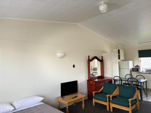 a room with a bed and two chairs and a television at Manhattan Motel in Rotorua
