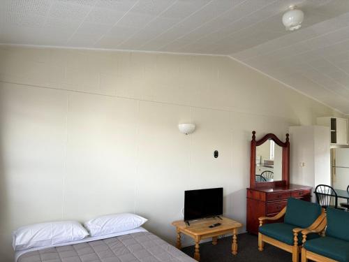 a bedroom with a bed and a tv and a chair at Manhattan Motel in Rotorua