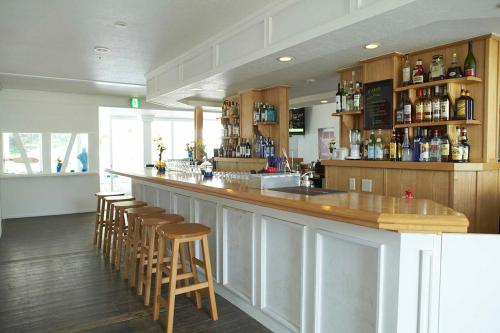 a bar with wooden stools and a counter in a restaurant at The Surf Lodge White Beach in Shimoda