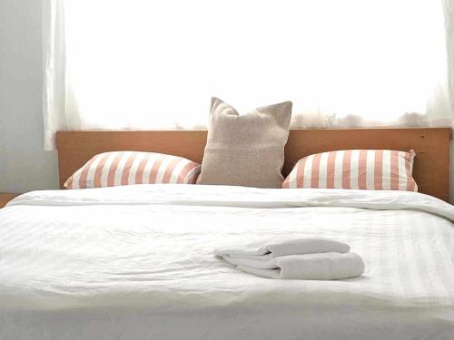 a white robe laying on a white bed with pillows at The Surf Lodge White Beach in Shimoda