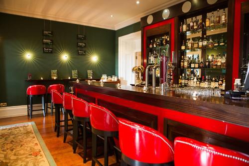 a bar with red chairs in a green room at The Lodge at Ashford Castle in Cong