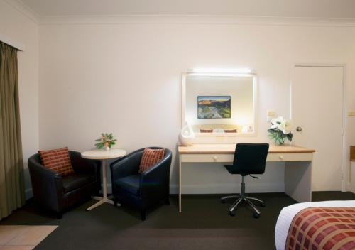 a hotel room with a desk and two chairs at Bowen Inn Motel in Lithgow