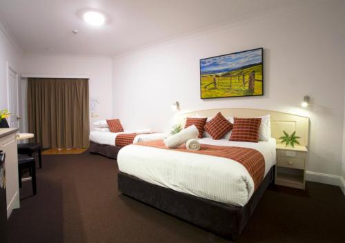 a hotel room with two beds and a desk at Bowen Inn Motel in Lithgow