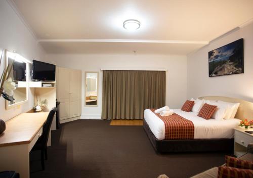 a hotel room with a bed and a desk at Bowen Inn Motel in Lithgow