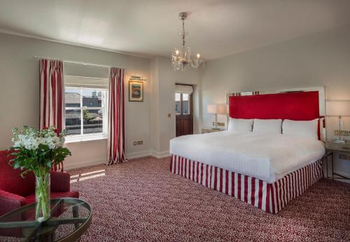 a bedroom with a large bed with a red headboard at The Lodge at Ashford Castle in Cong