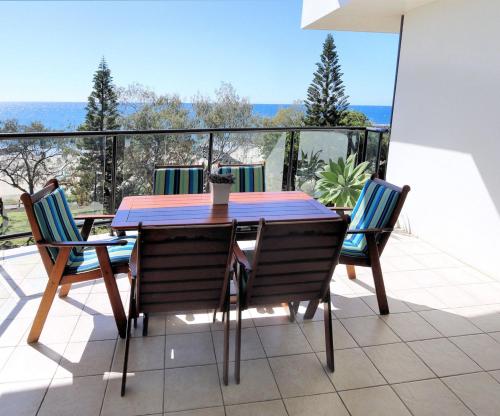 a table and chairs on a balcony with a view at 501 Pacific Reef in Bargara