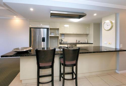 a kitchen with a counter and two bar stools at 501 Pacific Reef in Bargara