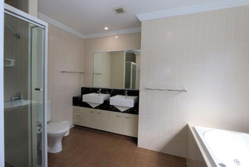 a bathroom with two sinks and a toilet and a mirror at 501 Pacific Reef in Bargara