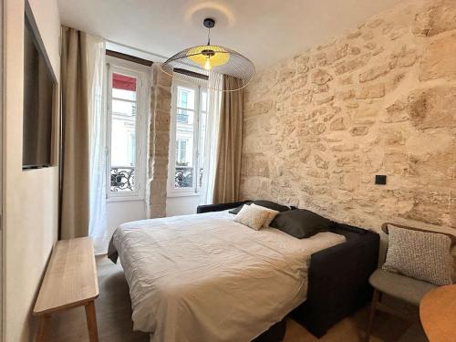 une chambre avec un lit et un mur en pierre dans l'établissement Louvre -Notre Dame 2BD, 2BATH AC, à Paris