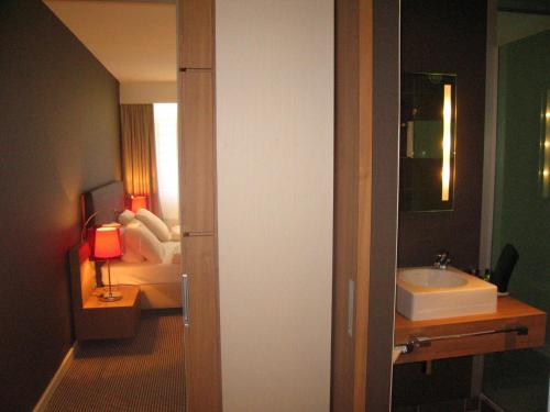 a room with a bathroom with a sink and a bed at Mercure Hotel Den Haag Central in The Hague