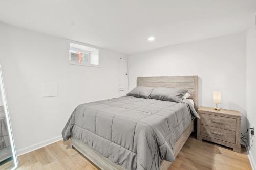 a white bedroom with a bed and a night stand at Negin 2903 - Basement Unit in Washington, D.C.