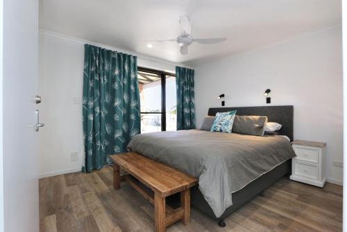 a bedroom with a bed with a bench and a window at Horizons Unit 4 Beachfront Unit in Bargara